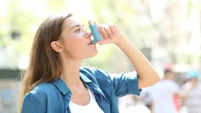 A woman is using an inhaler in her hand.